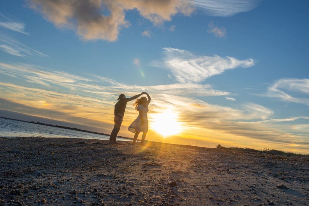 Couple holding hands on Boston beach during golden hour